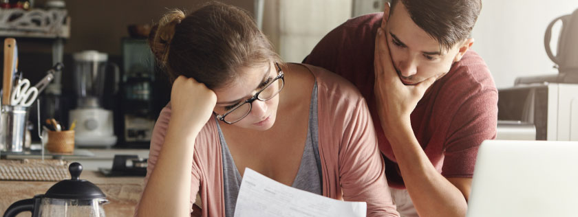 Young couple looking worried over bills